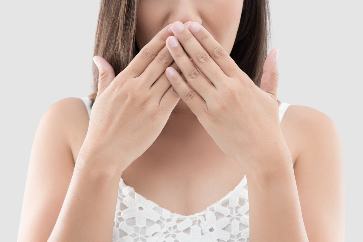 Woman with hands over mouth when bad breath won't go away