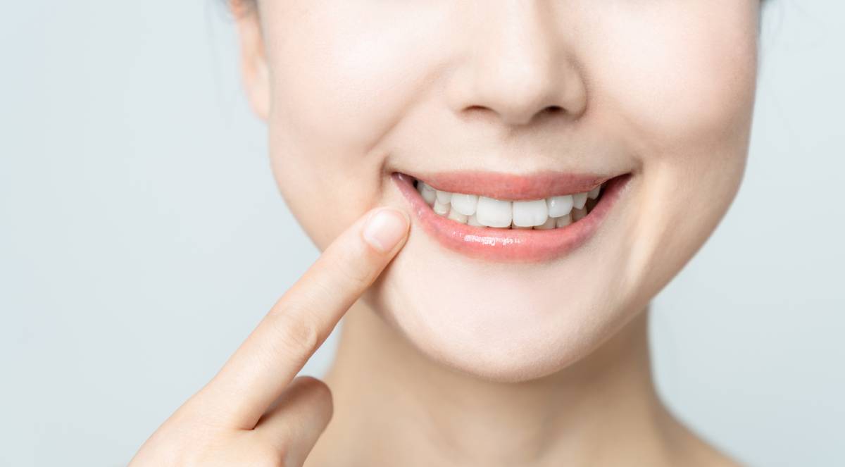 Woman smiling and pointing to her dental implants