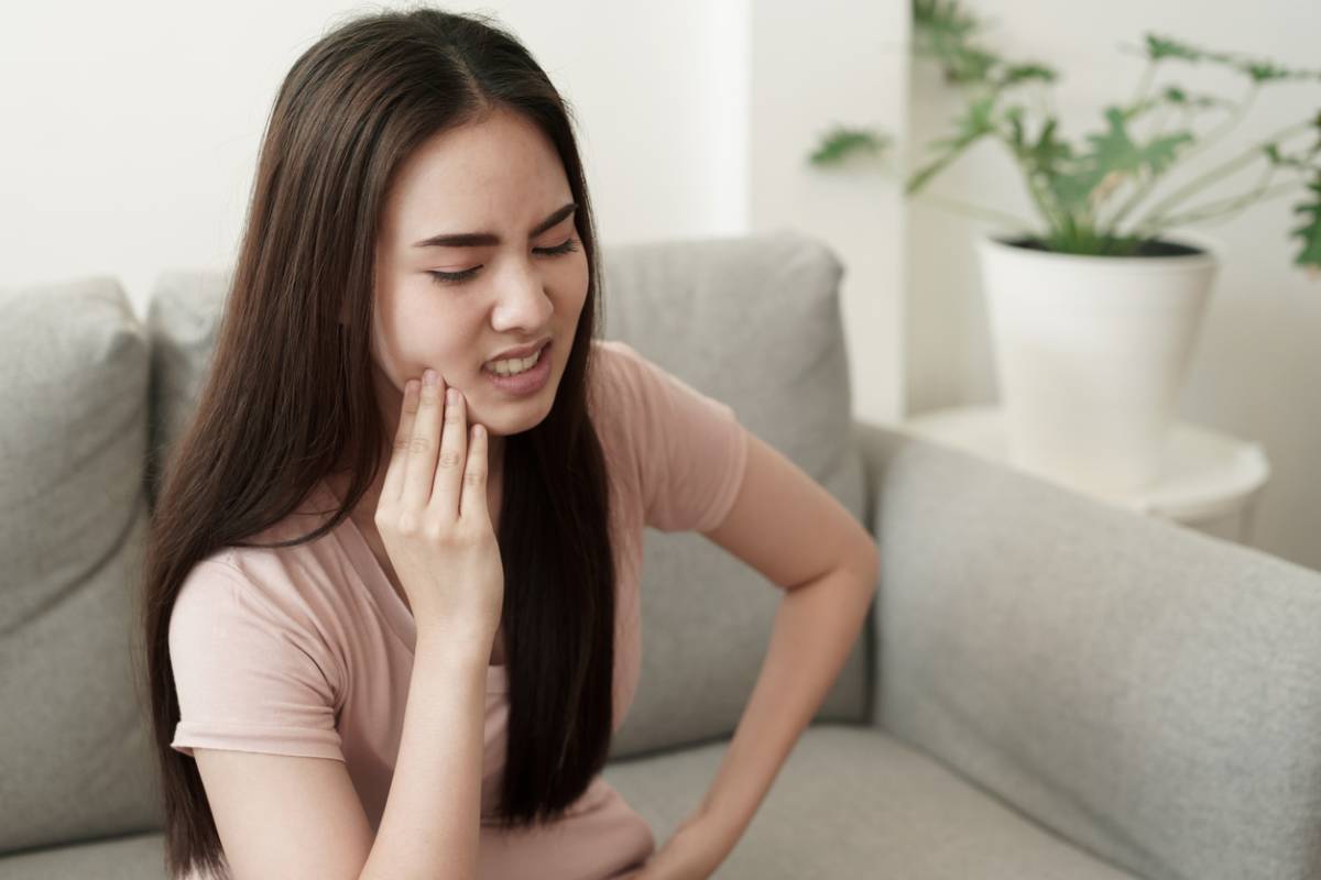 Women touching jaw due to toothache pain.